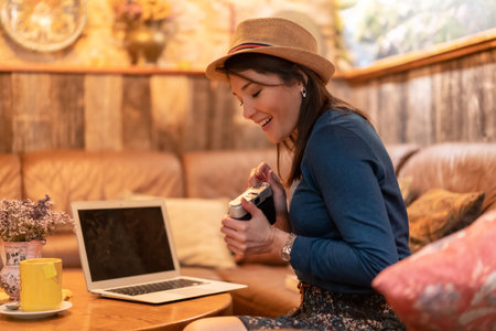 A pretty tourist in a hat and with a photo camera drinking tea in a coffee shop, having fun on a...