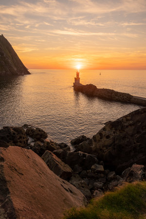 Orange sunset at the Lighthouse of the bay of Pasaia in the town of San Juan. Gipuzkoa. Basque Country, vertical photoの写真素材