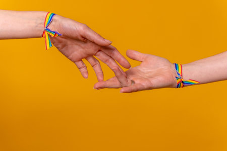 Hands of two women caressing and touching fingers, LGBT concept on a yellow background, couple of lesbian girlsの写真素材