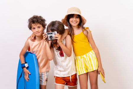 Kids summer vacation on a white background, boy taking a photo with vintage camera looking at camera