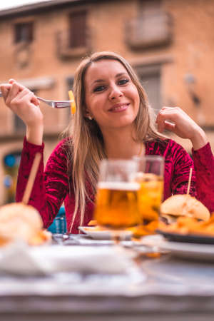 Blonde woman eating lunch in a red dress next to a medieval castleの写真素材