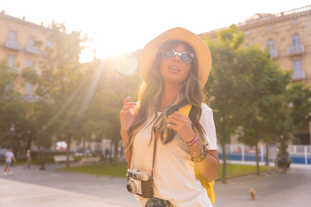 A tourist with a travel hat in the sunset, with a photo camera in the cityの写真素材
