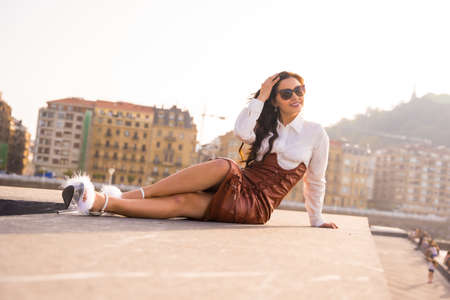 Portrait of a Latin woman in a sunset on vacation in the city by the sea with sunglassesの写真素材