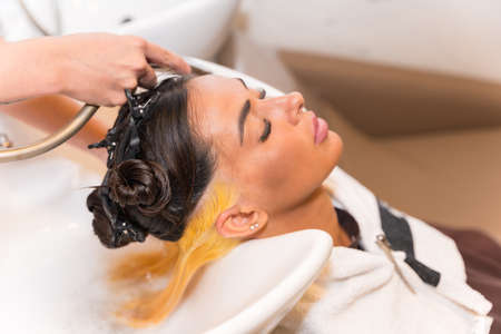 Hairdresser cleaning the hair with hot water and soap to a clientの写真素材