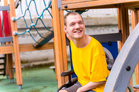 A disabled person in a wheelchair on the swings of a playgroundの写真素材
