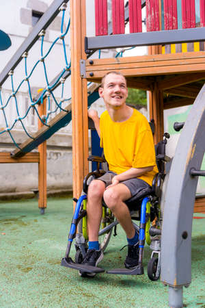 A disabled person in a wheelchair on the swings of a playground having funの写真素材