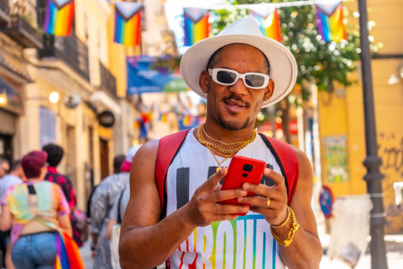 A gay black man at the pride party writing a message with the phone, LGBT flag