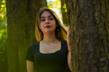 Portrait of a young woman next to a tree in nature in a natural parkの写真素材