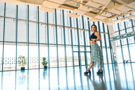 Portrait of a woman on the terrace of a viewpoint of the city in a glass building with a green skirtの写真素材