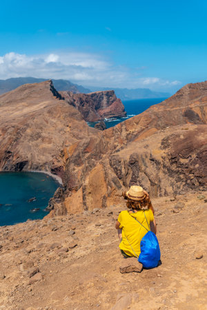 Young woman tourist sitting in summer in Ponta de Sao Lourenco looking at the landscape and the sea, Madeira coastの写真素材