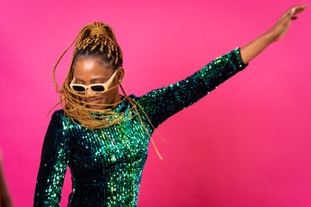 African young woman with party braids on a pink background, studio portrait in sunglassesの写真素材