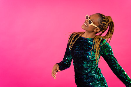 African young woman with party braids on a pink background, studio portrait having funの写真素材