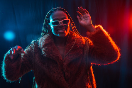 Young african woman with braids with blue and red led lights, having fun while dancingの写真素材