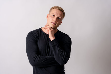 Attractive blonde german model in a black pullover on a white background, looking up with copy space