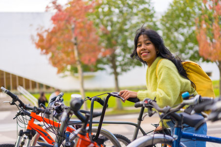 Portrait of smiling Asian female student parking bicycle at college campus