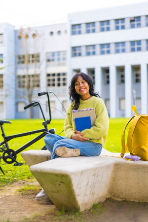 An asian female student smiling sitting in the university campus in the break from classes