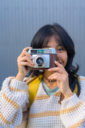 Portrait of a young Asian woman photographing with a vintage photo camera, vacation concept, tourist...