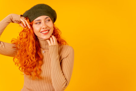 Red-haired woman in beret in studio on a yellow background, copy space, portrait pretty modelの写真素材