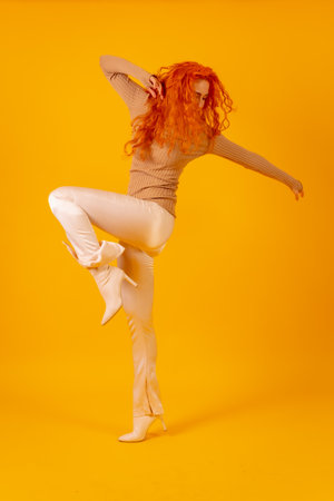 Red-haired woman on a yellow background, studio shot, fashion posed, full body in white bootsの写真素材