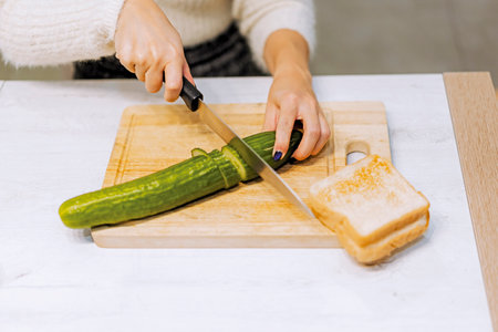 Vegetarian woman cooking a vegetable sandwich at home. cutting the dutch cucumberの写真素材