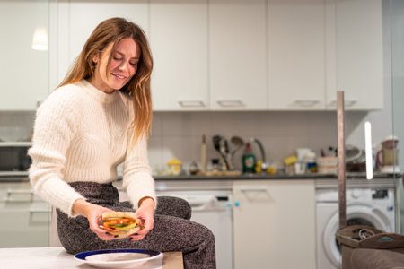 Vegetarian woman eating a vegetable sandwich in the kitchen at home. healthy nutritionの写真素材