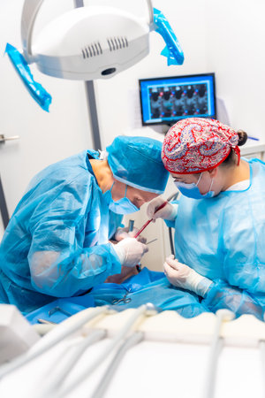 Doctors in blue gowns performing a complicated operation on a patient, flat action photoの写真素材