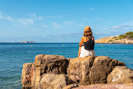 Vacation concept, A young woman in a hat by the sea in Ibiza at Salada y Saladeta beach. Balearicの写真素材