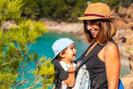 Vacation concept, mother with her baby in her backpack heading to Playa Salada and Saladeta in Ibiza. Balearicの写真素材