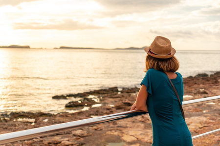 A young woman looking at the sunset on the Paseo de Poniente in San Antonio Abad, Ibiza Island. Balearicの写真素材