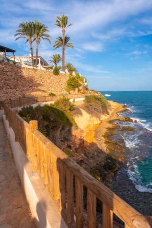 The beautiful red coast and palm trees next to the Caleta beach in summer in Cabo Roig. Alicanteの写真素材