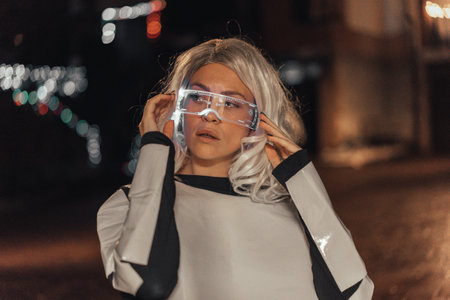 Portrait of woman with the illuminated futuristic glasses and white hair in the city, looking to the sidesの写真素材
