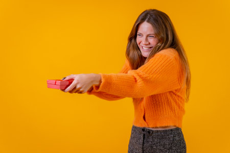 A woman delivering a gift as a surprise on a yellow background, Valentine's Day conceptの写真素材