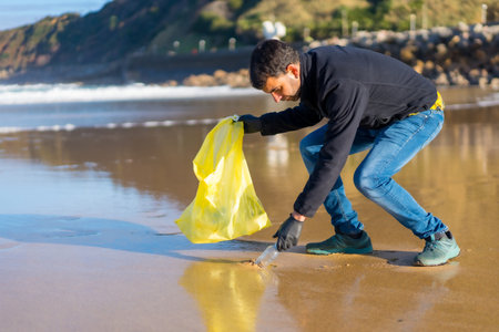 Volunteer man collecting garbage or plastic on the beach. ecology conceptの写真素材