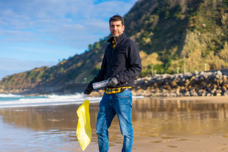 Volunteer portrait collecting garbage and plastic on the beach. Ecology concept, sea pollution