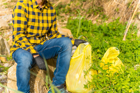 Unrecognizable person, resting from the collection of plastic and garbage in a forest. ecology,...