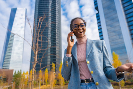 Corporate portrait of black ethnic businesswoman, business park, talking on the phoneの写真素材