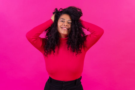 Curly-haired woman on a pink background, studio shot, lifestyle