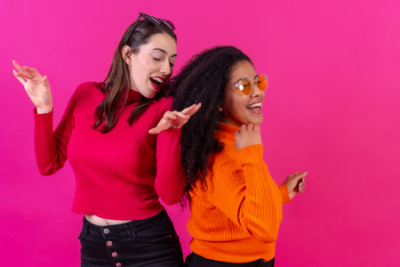 Female friends in sunglasses having fun pink background, studio shot, lifestyleの写真素材