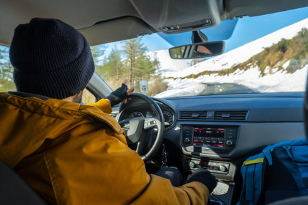 Cold wave, danger on the road, Man driving a car with snow on the mountain, view from inside