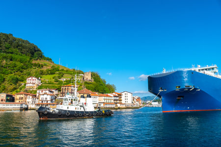 Cargo ship transporting a giant ship in the bay of Pasaia to the open sea Pasajes, Gipuzkoa, Spainの写真素材