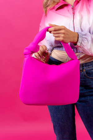 Hand of a woman with many pink handbag on a pink background, fashion studioの写真素材