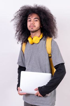 Young college boy with afro hair on white background, portrait with a computer on his arm