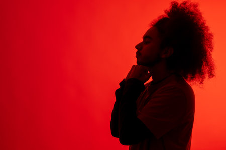 Silhouette with red light of boxer defending. Young man with afro hair on white backgroundの写真素材