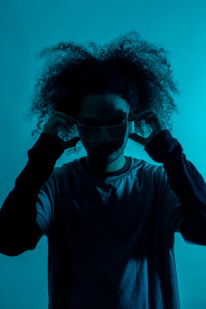 Future concept, silhouette with blue light with futuristic led glasses. Young man with afro hair on white backgroundの写真素材