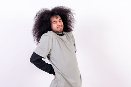 Suffering from back pain. Young boy with afro hair on white background