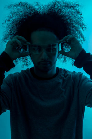 Silhouette with blue light with futuristic led glasses. Young man with afro hair on white backgroundの写真素材