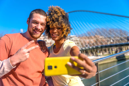 Multiracial couple through the city streets, lifestyle, selfie smiling by the river, victory gesture