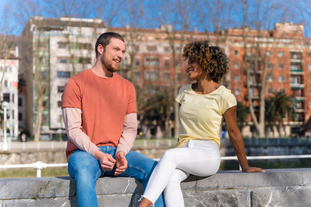 Multiracial couple on the city street, lifestyle, sitting smiling talking on the weekendの写真素材