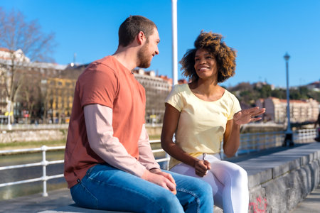 Multiracial couple on the streets of the city, lifestyle, sitting talking on the weekendの写真素材