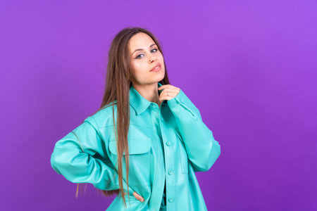 Close up portrait of a young caucasian woman in blue trench coat isolated on purple background, smilingの写真素材